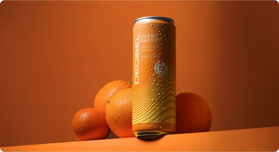 Orange flavored prebiotic energy drink on orange background, surrounded by oranges